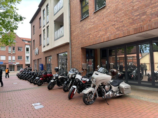 Mehrere Motorräder in verschiedenen Farben stehen vor einem Backsteingebäude im Freien