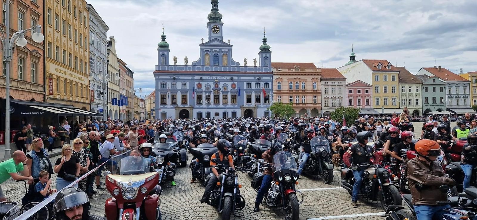 Viele Motorradfahrer und Zuschauer versammeln sich vor einem farbenfrohen Rathaus