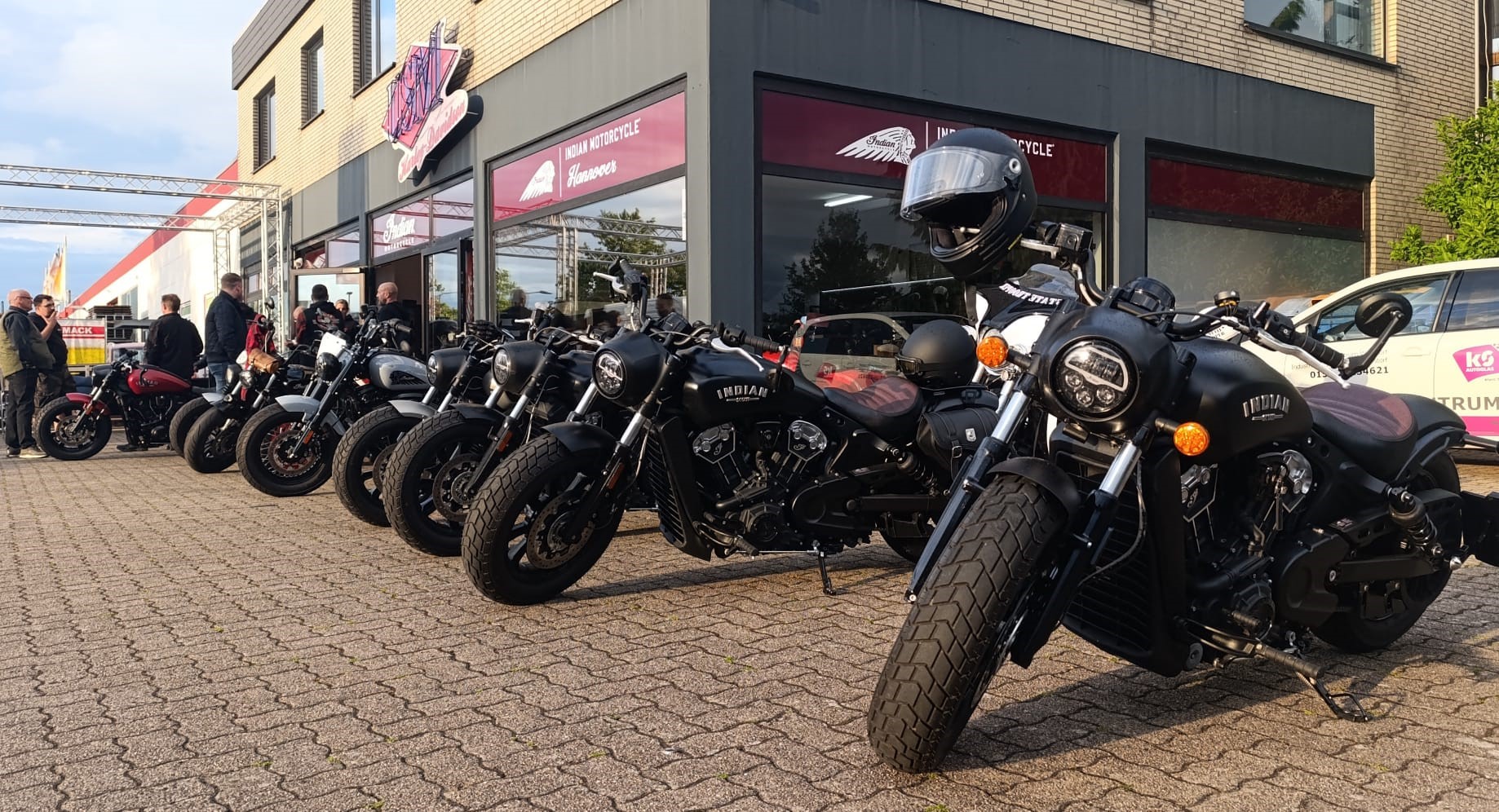 Eine Reihe schwarzer Motorräder steht vor einem Geschäft, einige Menschen sind zu sehen