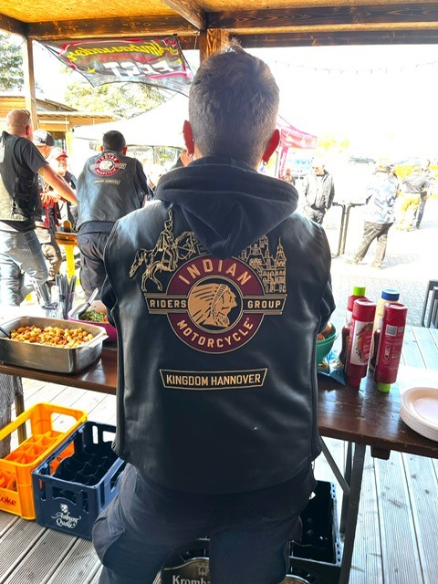 Ein Mann mit dunkler Lederjacke und Motorradlogo sitzt entspannt am Tisch