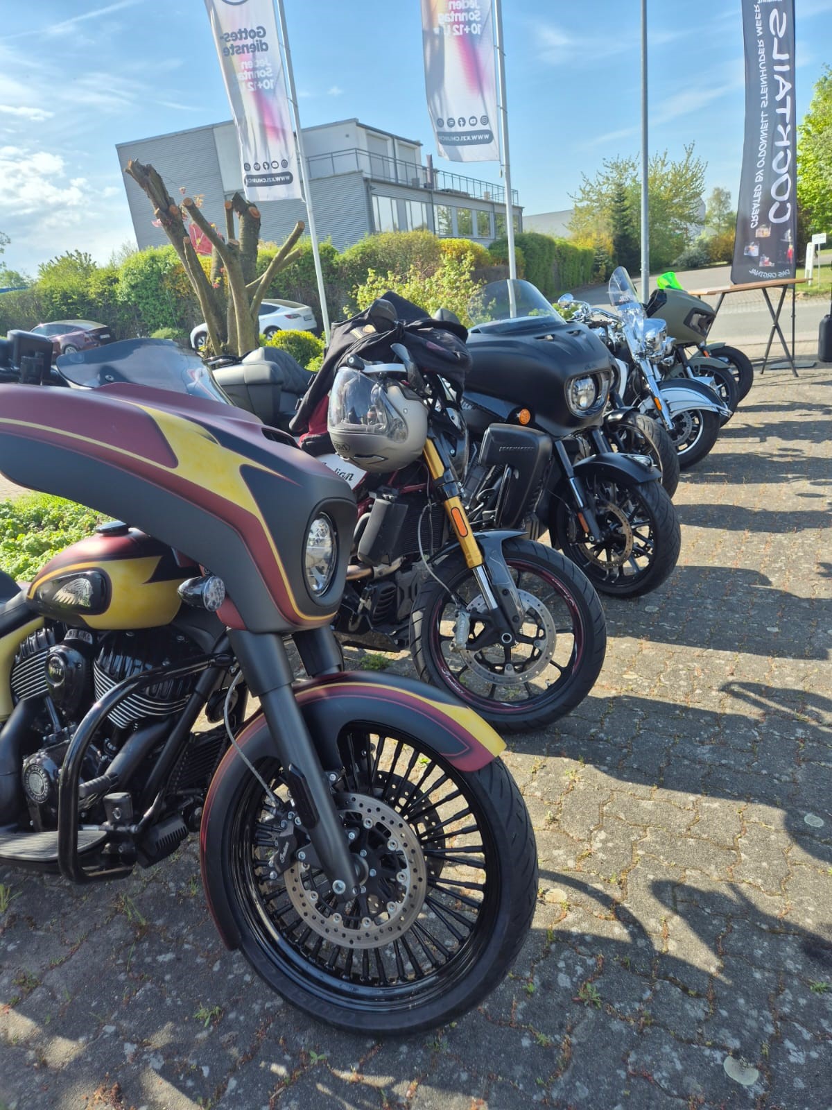 Mehrere auffällige Motorräder stehen nebeneinander auf sonnigem Asphalt