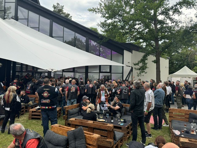 Viele Menschen mit dunkler Kleidung und Westen treffen sich in einem Außenbereich
