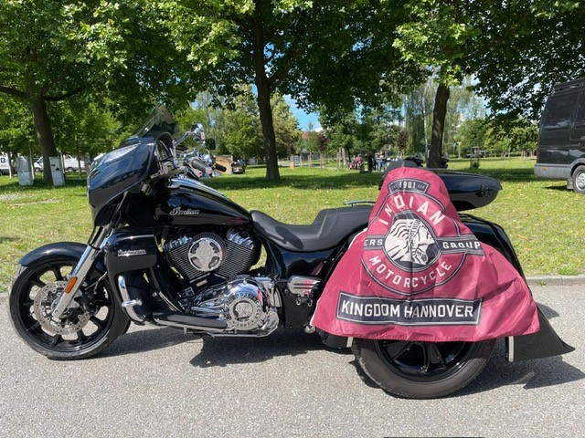 Ein schwarzes Motorrad mit glänzenden Chromteilen und einem auffälligen roten Banner